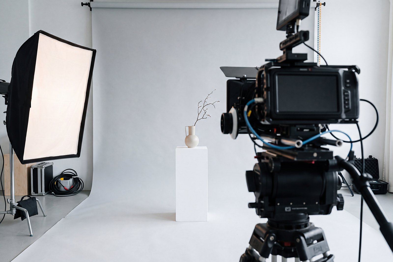 Kamera, Softbox und ein Produkt auf einem weißen Podest in einem hellen Fotostudio