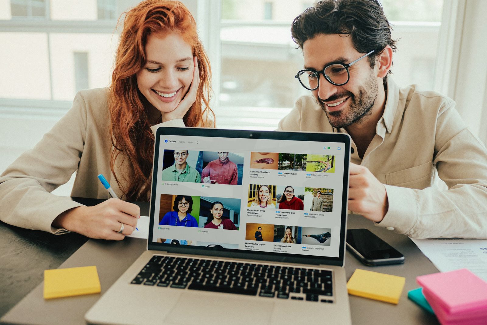 Eine Frau und ein Mann planen am Laptop Beiträge für Social Media, daneben liegt ein Smartphone