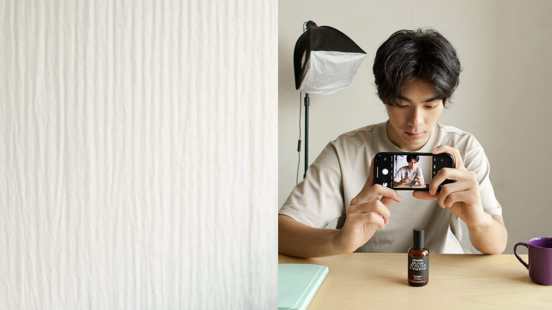 Ein junger Mann nimmt am Tisch mit dem Smartphone ein UGC-Video auf, vor ihm steht ein Pflegeprodukt